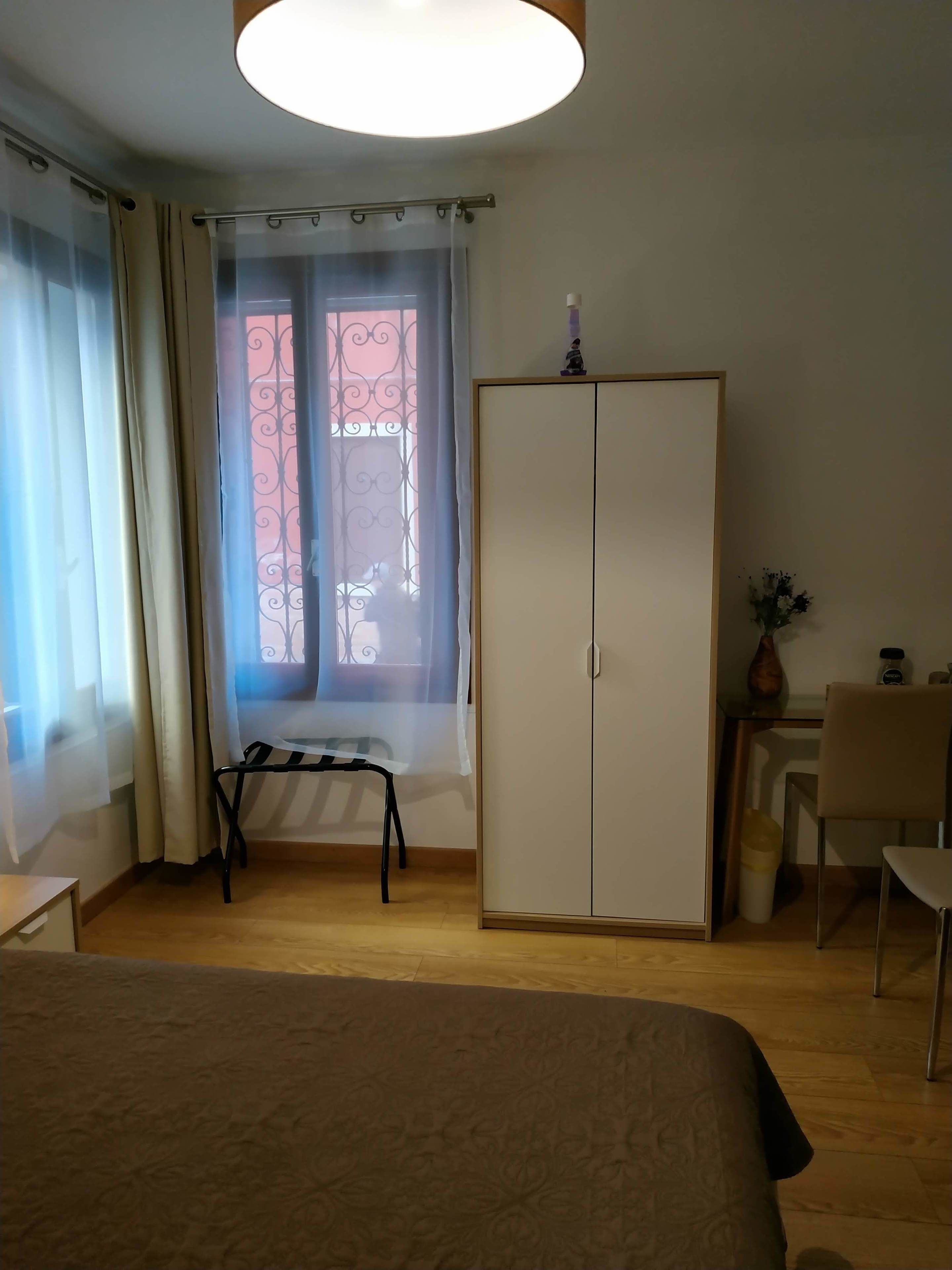 A bedroom with a bed, a wardrobe, a desk, and a chair.