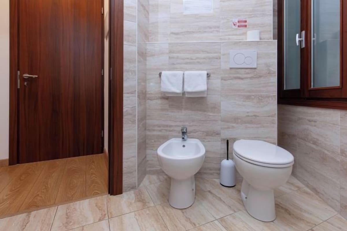 A modern bathroom with a bidet, toilet, and wooden door.