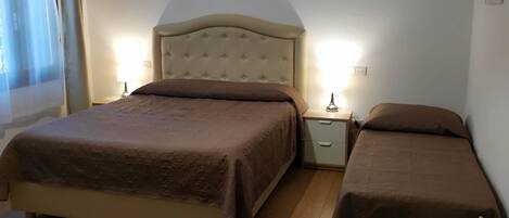 Quarto com uma cama grande, uma cama menor, uma cadeira e uma mesa de cabeceira com abajur.
