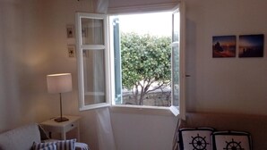 Una habitación con un ventanal grande, una lámpara, una cama y cuadros en la pared.