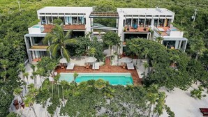 A modern villa with a pool, surrounded by lush greenery and a view of the ocean. - Tulsayab Luxury Development (Tulum)