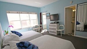 Een hotelkamer met twee bedden, een televisie, een bureau en een stoel.