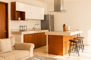 A modern kitchen with a central island, wooden cabinets, and a stainless steel refrigerator. - The Strabon Tulum (Tulum)