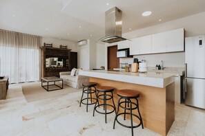 Una cocina moderna con una isla central, taburetes de bar y horno empotrado.