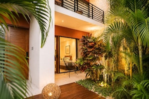 A modern house with a wooden deck, indoor seating area, and lush tropical plants. - The Strabon Tulum (Tulum)