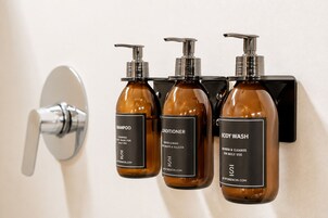 Trois flacons de produits de toilette sont disposés sur un distributeur mural.