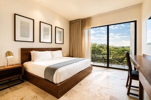 A hotel room with a large bed, a desk, and a view of the outdoors.