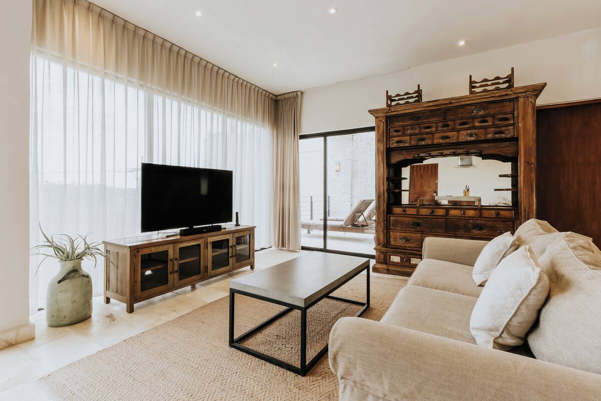 Una sala de estar moderna con un televisor de pantalla plana, un mueble de madera y un sofá grande.