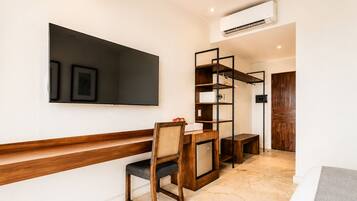 Una habitación moderna con un banco de madera, un escritorio con una silla, un televisor montado en la pared y un armario.