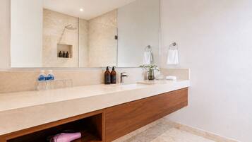 A modern bathroom with a large mirror, a shower, and a vanity with a sink.