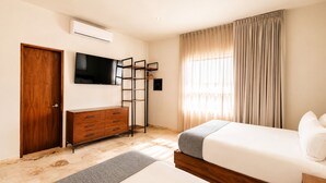 A bedroom with a bed, a dresser, a TV mounted on the wall, and a window with curtains. - The Strabon Tulum (Tulum)