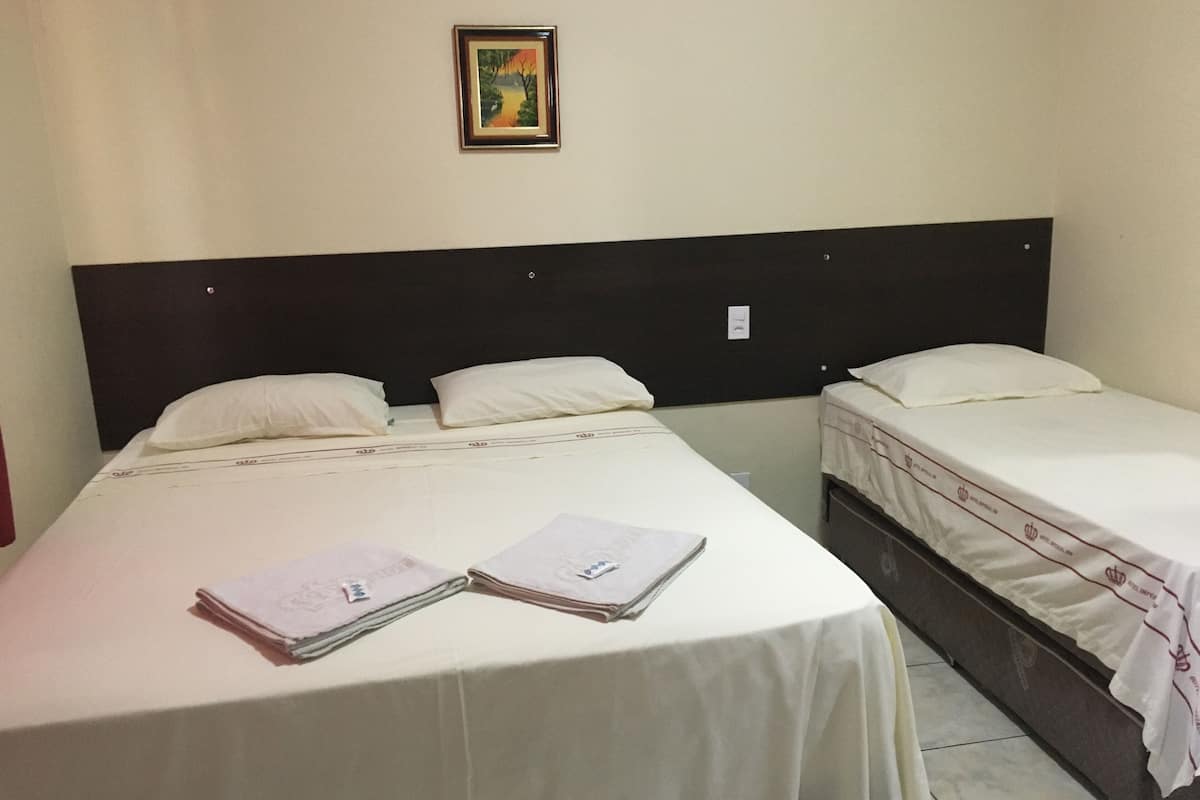 Ein Hotelzimmer mit zwei Betten, einem Kopfteil und einem gerahmten Bild an der Wand.