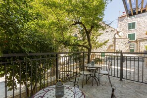 An outdoor seating area with a table and chairs, surrounded by a stone wall and a metal fence. - Luxury Room Miara in Split City Center III (Split)