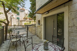 A stone building with a balcony featuring a table and chairs, a door, and a view of the street. - Luxury Room Miara in Split City Center III (Split)