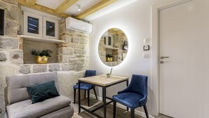 A cozy room with a stone wall, a wooden ceiling, a round mirror, a sofa, two chairs, and a door. - Luxury Room Miara in Split City Center I (Split)