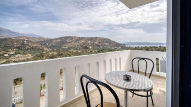 A balcony with a table and chairs, overlooking a mountainous landscape. - Creta Star Apartments (Agios Vasileios)