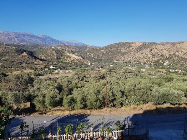 A rural landscape with a road, houses, and mountains in the background. - Creta Star Apartments (Agios Vasileios)