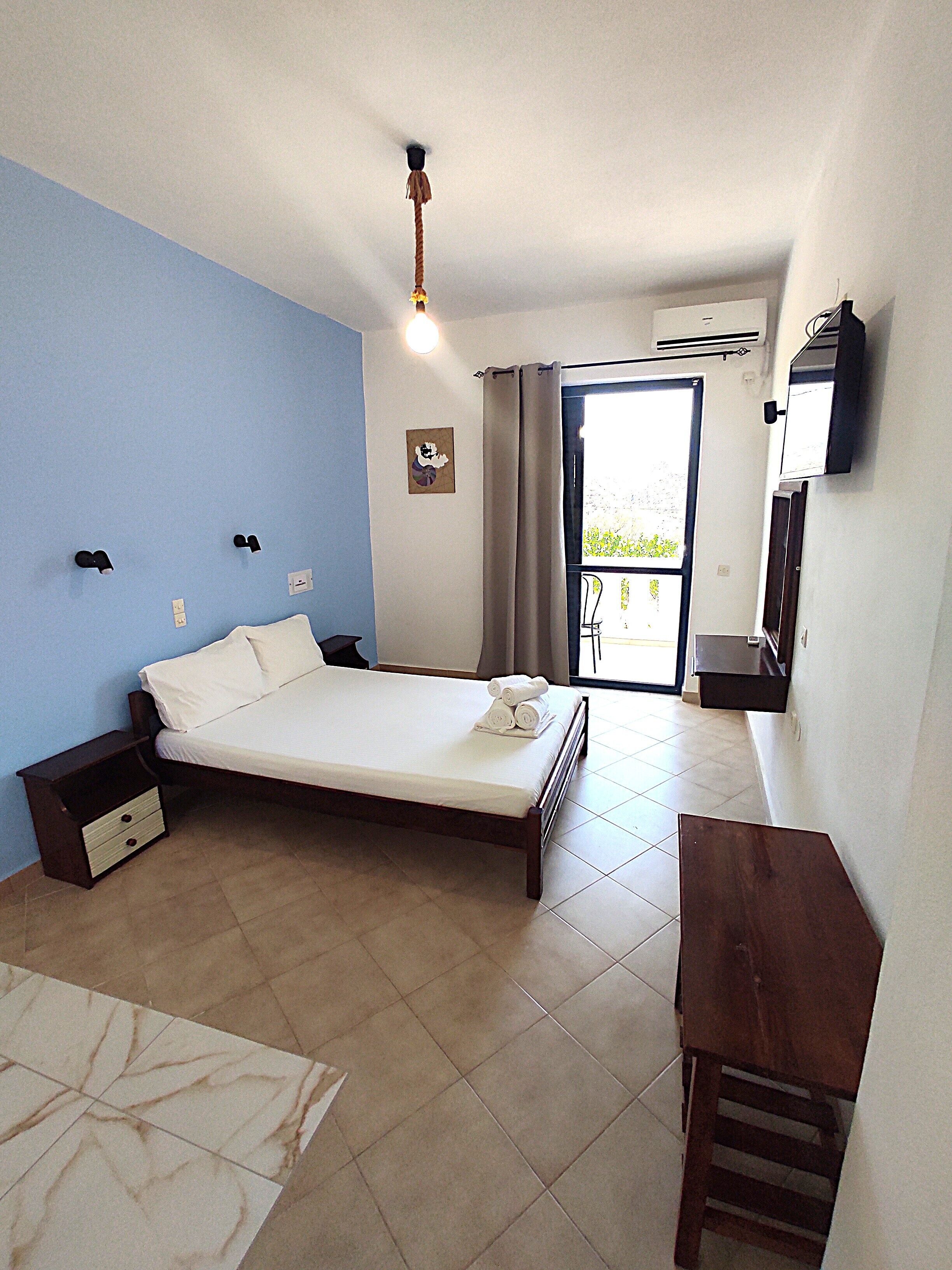 A bedroom with a bed, bedside table, and a desk.