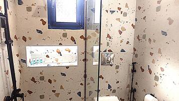 Ein kleines Badezimmer mit Dusche, Toilette und Fenster.