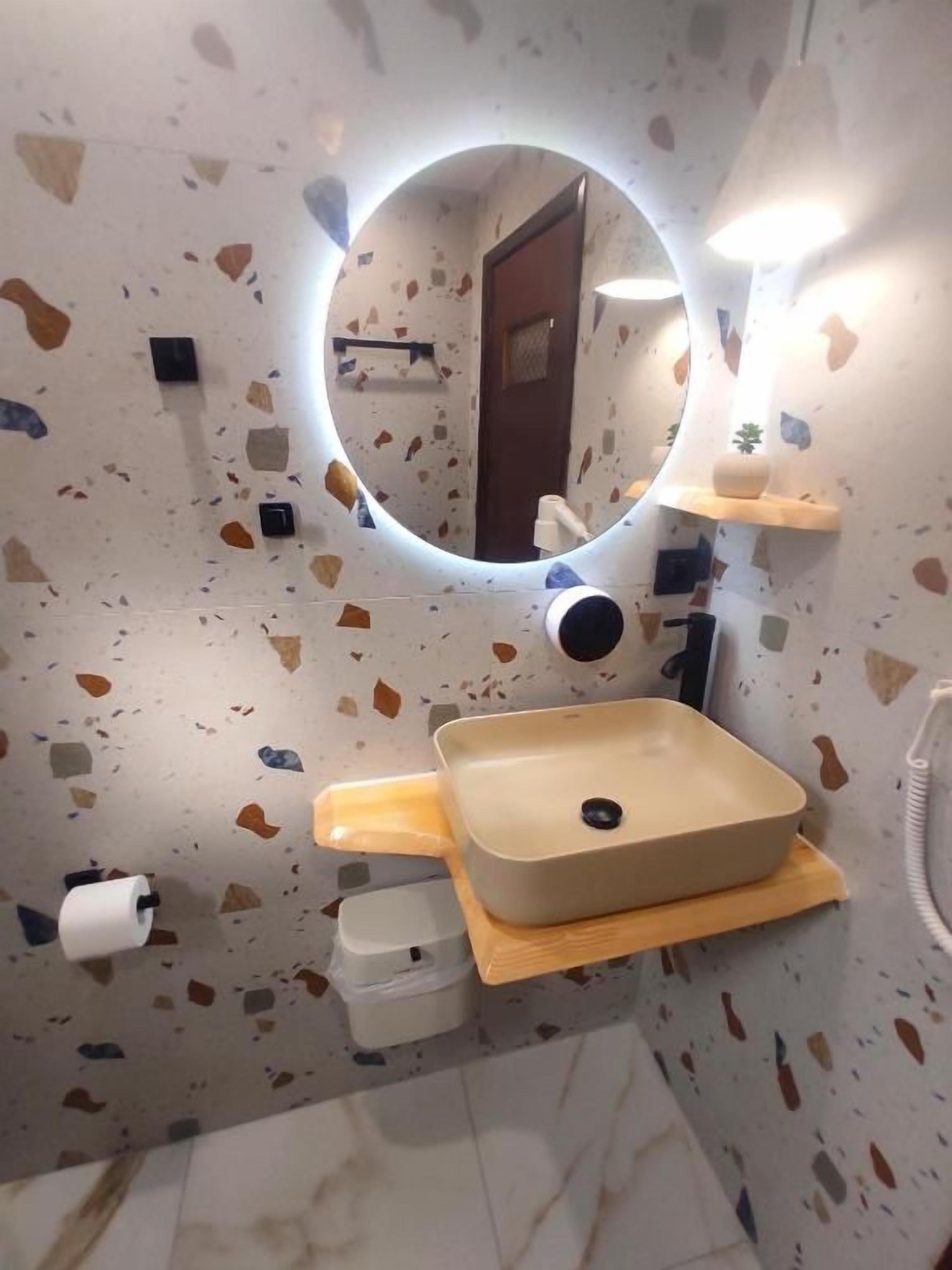 A bathroom with a round mirror, a sink, and a toilet.