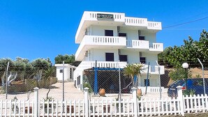 A multi-story Creta Star Apartments building with balconies, surrounded by a white picket fence and a chain-link fence. - Creta Star Apartments (Agios Vasileios)