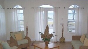 A spacious living room with two sofas, a coffee table, and a large window with curtains.