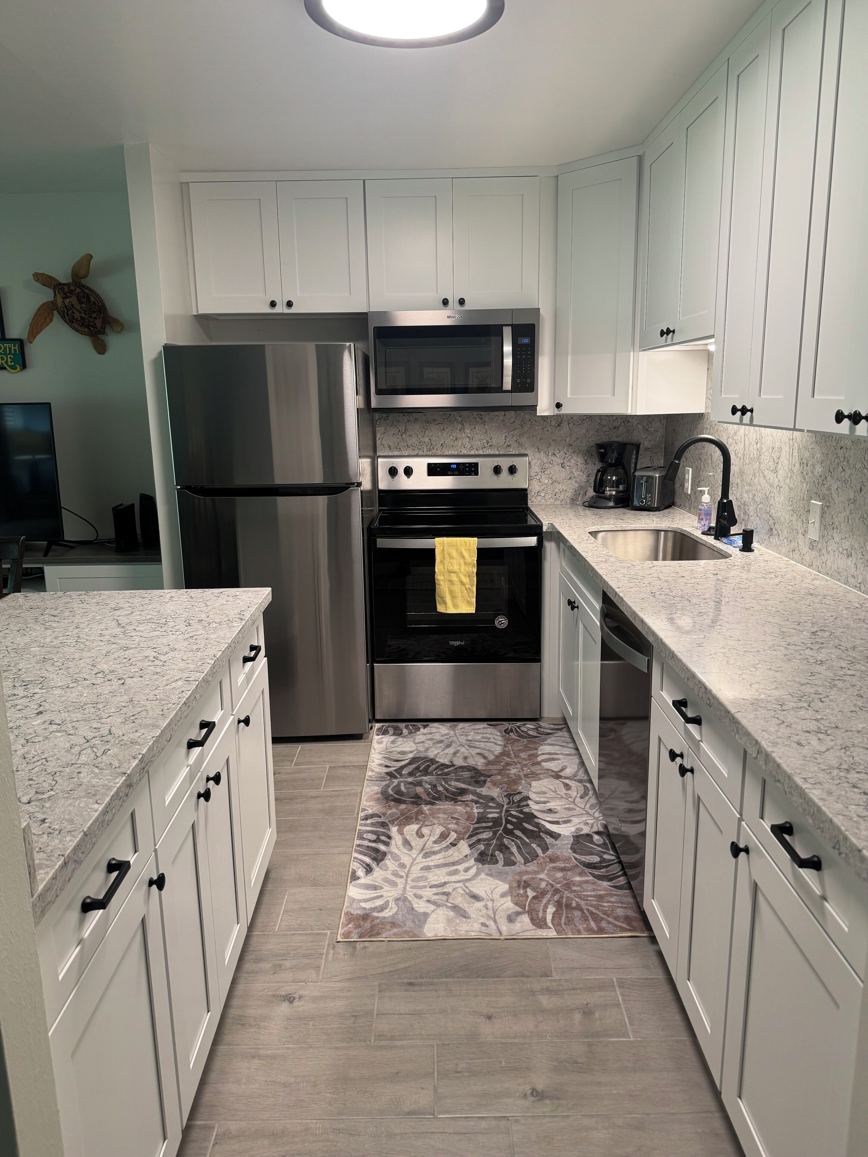 A modern kitchen with white cabinets, stainless steel appliances, and a granite countertop.