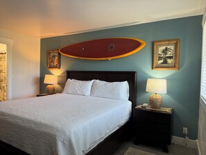 A neatly made bed with white linens, a dark wooden headboard, and two bedside lamps. - Remodeled 2025, king bed, 2 Bathroom, sleeps 4 (Kahuku)