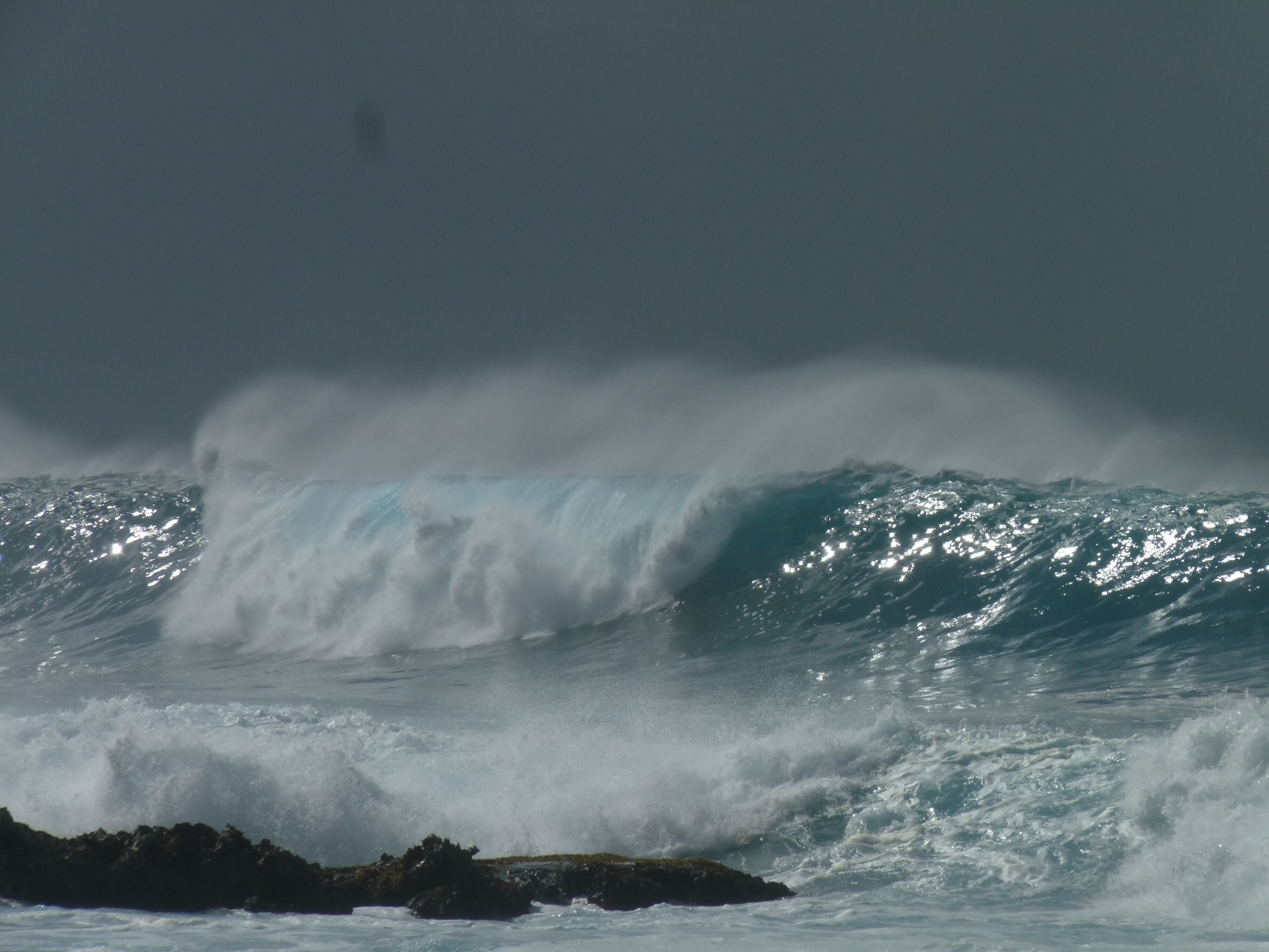 Une grosse vague qui s’écrase contre une côte rocheuse.