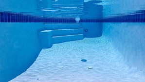 Ein Blick unter Wasser auf einen Swimmingpool mit klarem, blauem Wasser, Kachelfliesenboden und sichtbarer Pooltechnik.