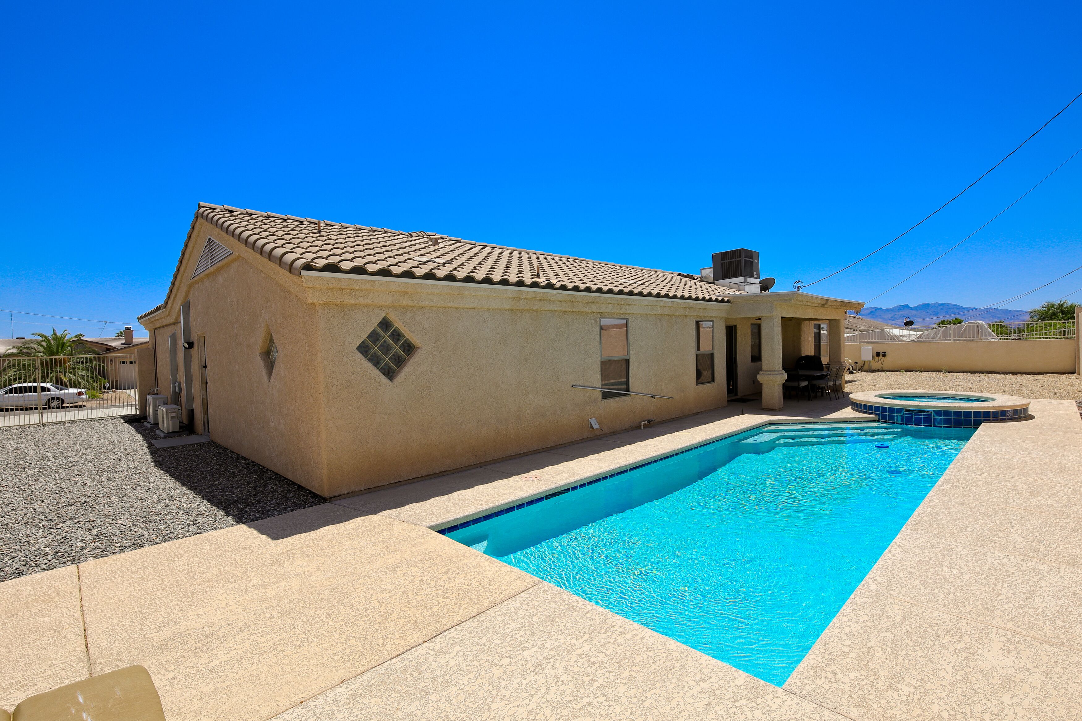 A residential property with a swimming pool, a covered patio, and a view of mountains.