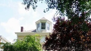 A yellow house with a front porch, a garden with various plants, and a pathway leading to the entrance.