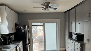 A modern kitchen with grey cabinets, a black refrigerator, a built-in oven, and a large island with a marble countertop.