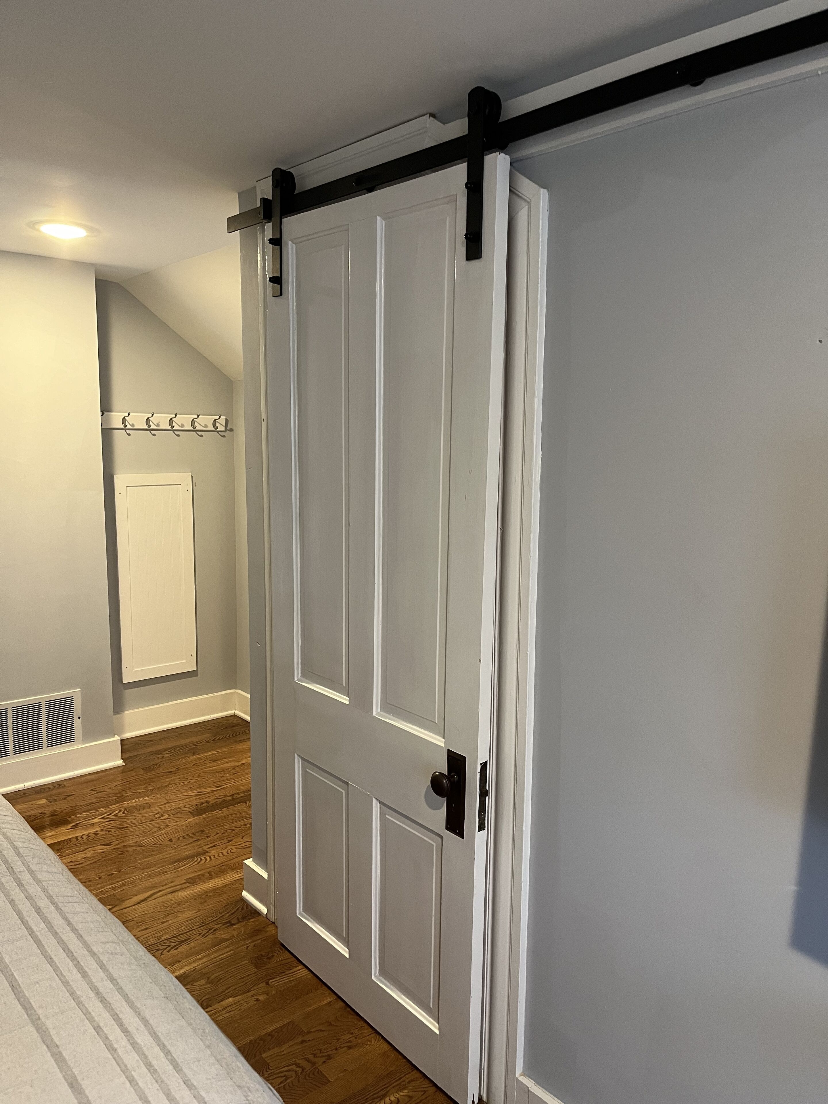 Une pièce avec une porte blanche, un porte-manteau et un plancher en bois.