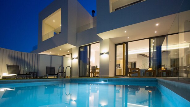 A modern building with a swimming pool, large windows, and a staircase leading to an upper level.