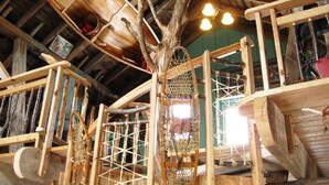 Ein rustikales Holzinterieur mit hohen Decken, freiliegenden Balken und einem großen Baumstamm.