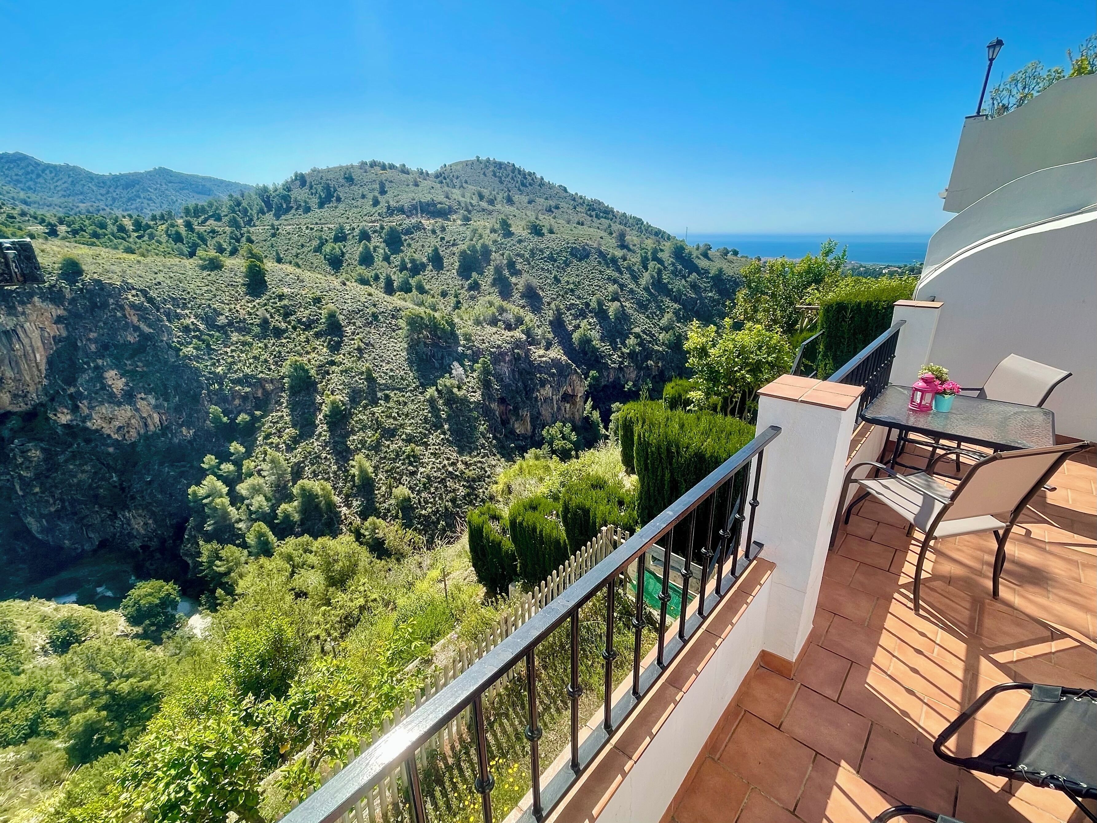 Un balcón con mesa y sillas con vistas a un paisaje montañoso.