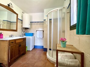 A bathroom with a sink, mirror, wooden cabinets, a washing machine, a shower, and a small table with a potted plant. - HOLIDAY RENTAL APARTMENT ... 5 KM TO THE NEAREST BEACHES, WIFI, SUNNY TERRACE. GARDEN (Frigiliana)