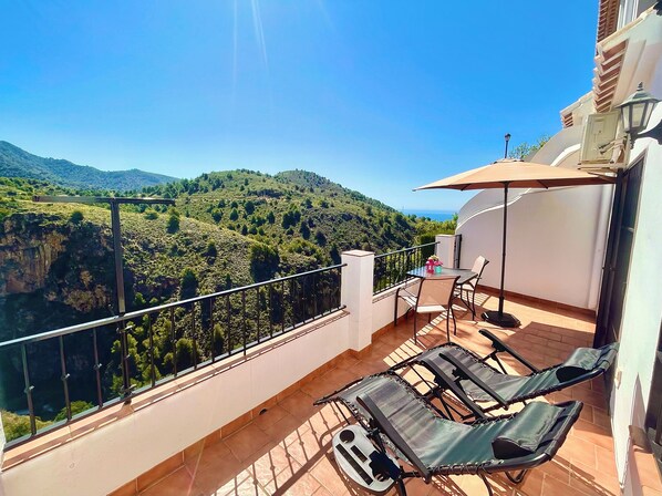 A balcony with a table and chairs, overlooking a mountainous landscape. - HOLIDAY RENTAL APARTMENT ... 5 KM TO THE NEAREST BEACHES, WIFI, SUNNY TERRACE. GARDEN (Frigiliana)