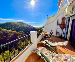 A balcony with a view of a hilly landscape, a table with chairs, and a railing. - HOLIDAY RENTAL APARTMENT ... 5 KM TO THE NEAREST BEACHES, WIFI, SUNNY TERRACE. GARDEN (Frigiliana)