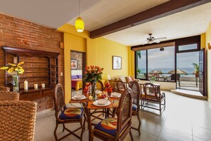 Enjoy meals in this cozy dining area with a large table, wicker chairs, and a brick wall.