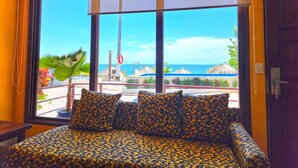 Ein Zimmer mit einem Bett, großen Fenstern und Blick auf den Strand.
