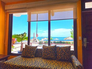Enjoy a beachside view from the large window, featuring a comfortable bed with a patterned bedspread and matching pillows.
