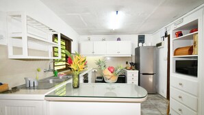 Een moderne keuken met witte kasten, een roestvrijstalen koelkast en een glazen kookeiland met een bloevas.