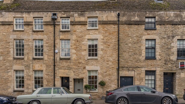 A stone building with multiple windows and doors, parked cars, and a sign indicating a property for sale. - New Church Cottage  - sleeps 4 guests  in 2 bedrooms (Tetbury)