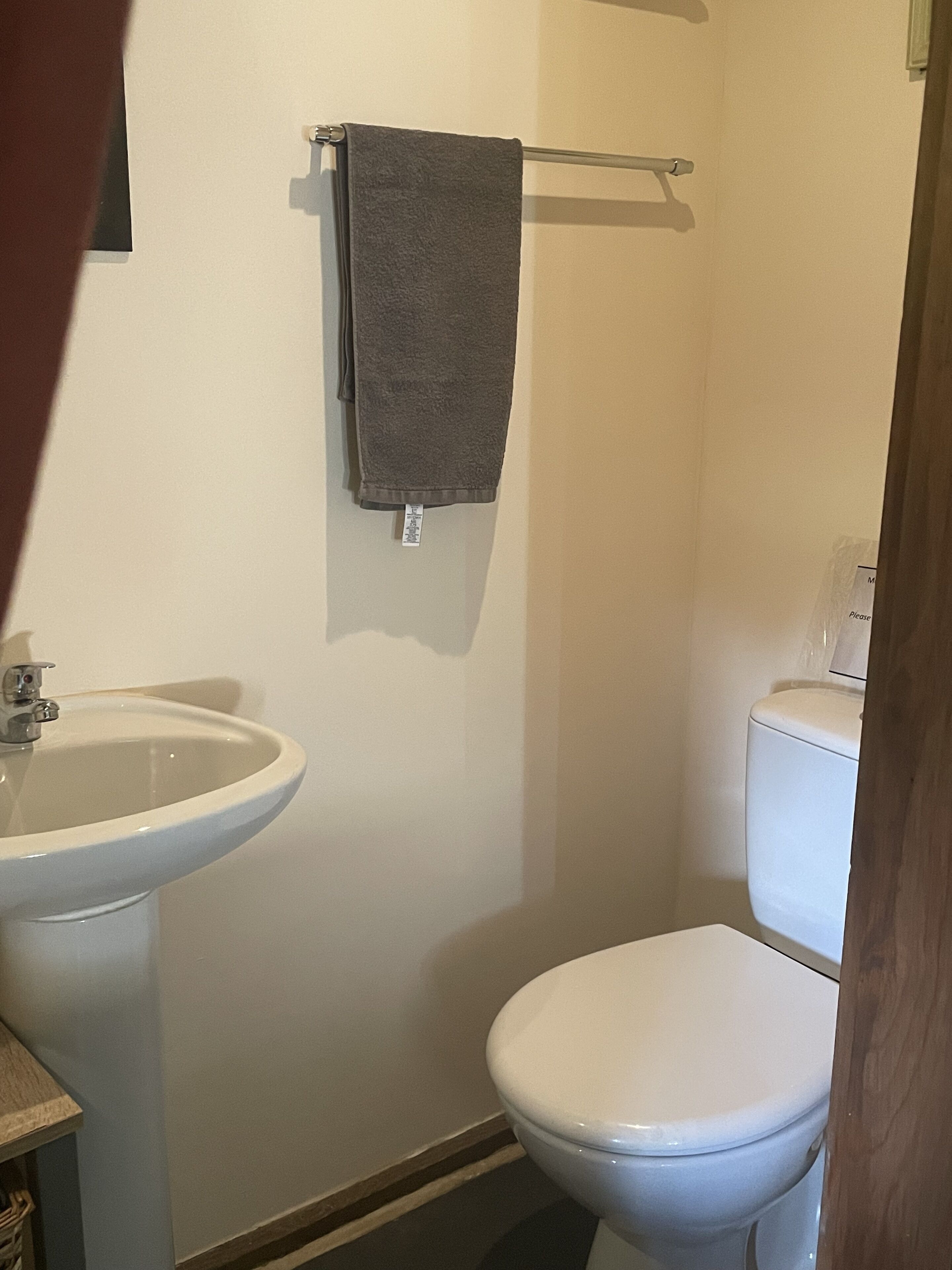 Une salle de bain avec un lavabo blanc, des toilettes et une serviette suspendue à un porte-serviettes.
