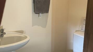 Une salle de bain avec un lavabo blanc, des toilettes et une serviette suspendue à un porte-serviettes.