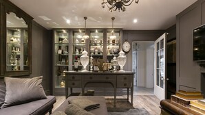 A modern living room with a sofa, a coffee table, and a bookshelf filled with decorative items. - High View Large Luxury House (London)