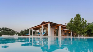 A poolside area with a covered seating area and lounge chairs.