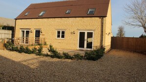 A two-story stone building with a sloped roof and multiple windows. - Lovely Cotswold holiday cottage within walking distance of restaurants/shops   (Bourton on the Water)